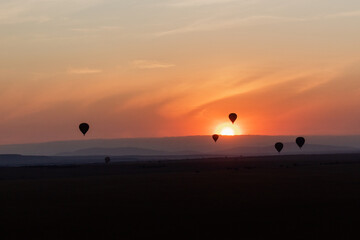 Air balloons flying in sunrise under African savannah