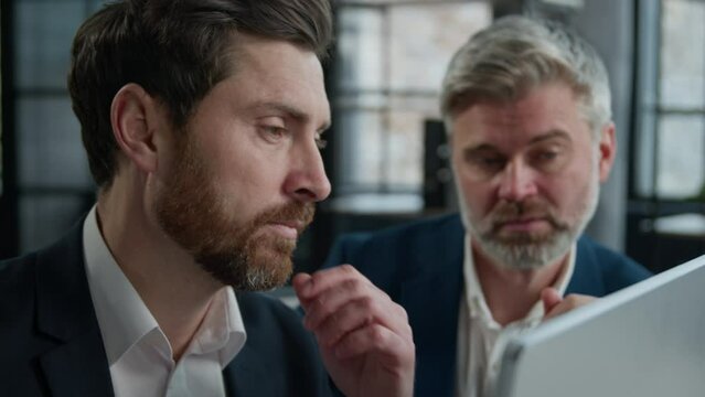 Two caucasian businessmen men business partners partnership discussing financial market data using laptop computer mentor advisor manager consulting investor client with online technology in office