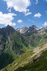 Fototapeta premium View of the swiss alps with green meadows and high barren peaks among a blue sky backdrop in the Kanton Uri Switzerland 