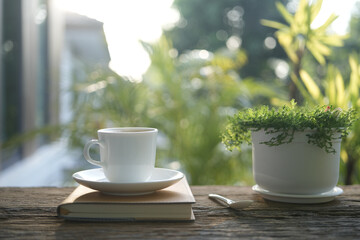 Coffee cup and plant and notebook on wooden table outdoor