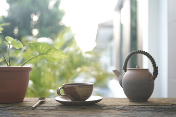earthenware tea cup and tea pot and plant pot on wooden table outdoor relaxing drinking
