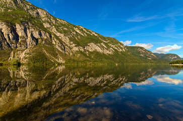 Fototapeta na wymiar Astonishing panoramic nature landscape of scenic mountain range which reflected in turquoise water of Bohinj Lake, Triglav National Park, Slovenia. Concept of landscape and nature