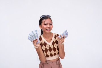 A young asian woman happily holding a tidy amount of cash. Flaunting her wealth. Isolated on a white background.