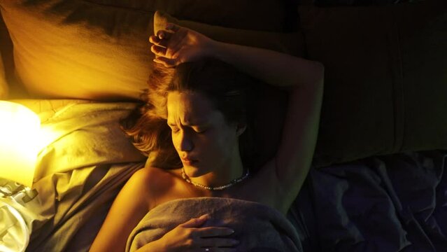 beautiful woman lies in bed at night, light from a floor lamp. The concept of rest and relaxation in a dream.