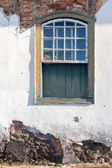 Aged and damaged window in a rustic style on the wall of the abandoned rural house. Diamantina, Minas Gerais, Brazil