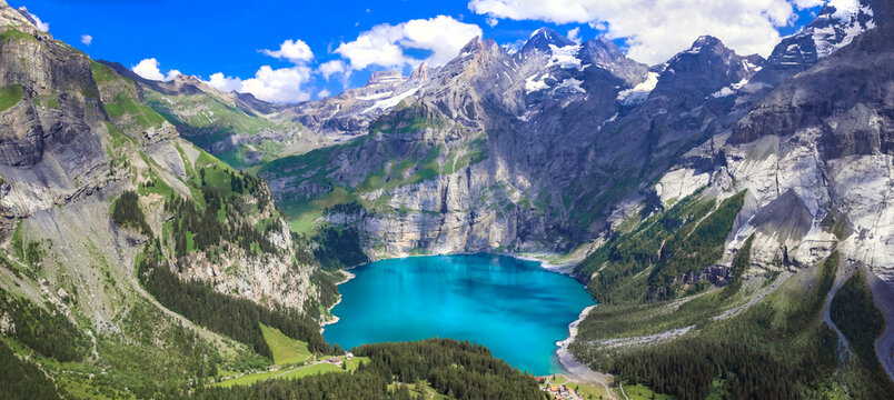 Idyllic swiss mountain lake Oeschinensee (Oeschinen) with turquise water and snowy peaks of Alps mountains near Kandersteg village aerial high angle view. Switzerland nature scenery