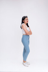 A pensive young woman looking upset while crossing her arms. Looking at someone, maybe her boyfriend. Whole body photo isolated on a white backdrop.