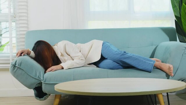 Tired woman sleeping closed eyes on sofa in living room at home after overworked working, Asian female resting falling asleep lying on couch, Full body