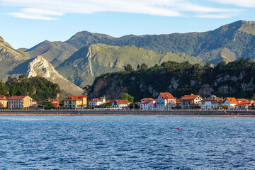 Residential area facing the beach and the sea at high tide between mountains the coastal town of Ribadesella at sunset, Asturias, Spain