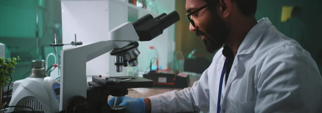 In the laboratory young face man scientist with glasses and protective gloves holding a tube. Medicine, biotechnology, chemistry