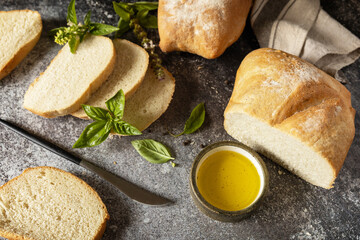Fresh crispy Ciabatta bread. Sliced Italian ciabatta bread with extra virgin olive oil and herb on a dark stone background.