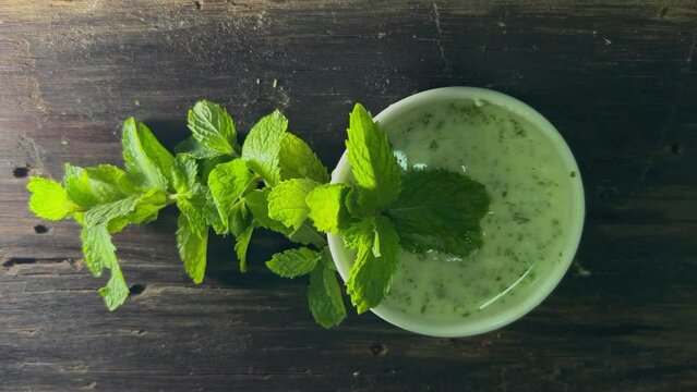 Yogurt Green Mint sauce with mint leaves and white serving bowl on the wooden plate ,