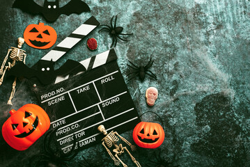 Halloween movies concept. Movie clapperboard with funny halloween pumpkin,skeletons and spiders. Halloween concept background