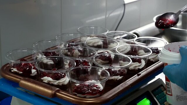 The confectioner puts the jam into the dessert, weighing it on a kitchen scale. Ice cream preparation.