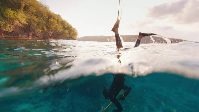 Sea spearfishing. Freediver inhales and dives with speargun. Underwater view of the freediver hunting with speargun