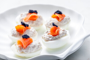 boiled eggs filled with tuna fish spread and smoked salmon and  black caviar on the top