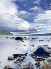 Loch Ness and cloudy blue sky. Selective focus on the rocks on foreground.