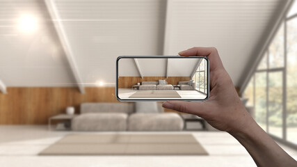 Augmented reality concept. Hand holding smart phone with AR application used to simulate furniture and interior design products in real home, mezzanine living room - obrazy, fototapety, plakaty