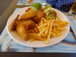 Deep fried chicken wings with fried potatos