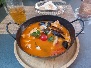 Seafood spicy soup with potatoes, shrimps, mussels, herbs and fish from a picad closeup served with bread - obrazy, fototapety, plakaty