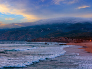 Sunset summer Atlantic Ocean rocky coast with sandy beach (Guincho, Portugal).