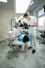 Dentist uses a photo camera to examine a patient.