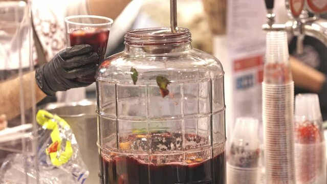 Hot mulled wine is poured from a vat into plastic cups at the fair