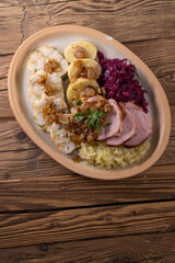 smoked meat served with red and white cabbage and two kinds of dumplings