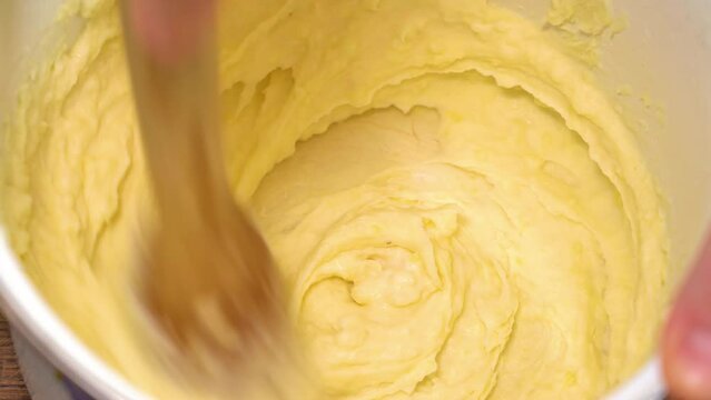mashed potatoes are stirred with a wooden masher