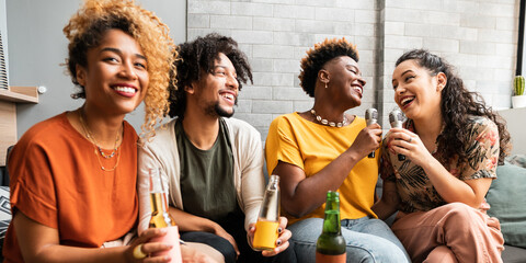 Friends sing excited karaoke on the sofa in the living room at home