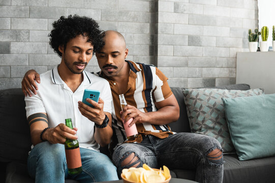 Couple in love use mobile phone together on sofa in living room at home