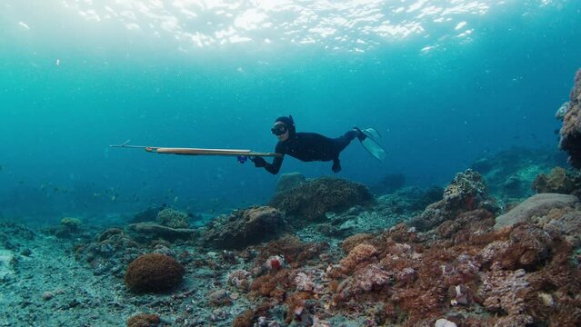 Sea spearfishing. Man spearfishes in the sea with speargun and slowly swims in search of target. Underwater view of the freediver hunting with speargun
