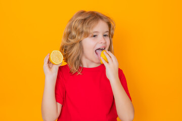 Healthy fruits for kids. Child eat lemon in studio. Studio portrait of cute kid boy lick lemon isolated on yellow.