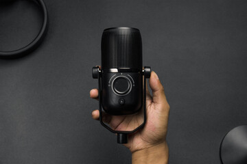 man hand holding condenser mic with plain black background