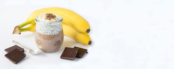 Chocolate pudding with chia seed and banana in the glass jar on the white background. Copy space.
