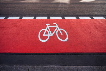 bicycle icon road marking on a red bike lane on a street in the city - obrazy, fototapety, plakaty