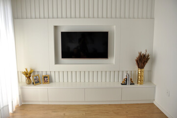 sala de estar com tv e ripado branco com decoração dourada 