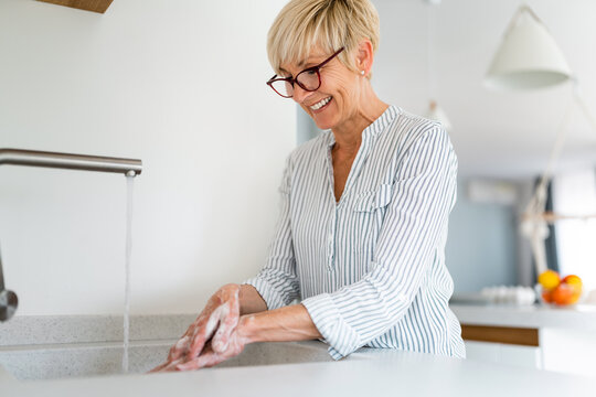 Happy Joyful Older Blonde Woman After Doing Prevention By Carefully Washing Hands With Soap At Home.