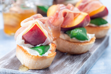 Delicious prosciutto peach bruschetta. Crostini, cream cheese, basil, peach, prosciutto, horizontal
