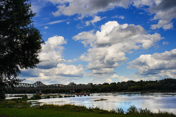 Widok na rzekę Wisłę i most, oraz błękitne niebo pełne białych chmur