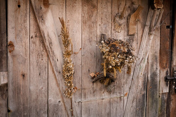 Drewniana ściana z wiszącymi na niej zasuszonymi roślinami.