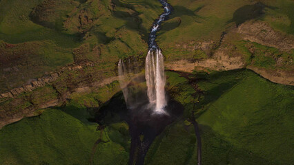 The Seljalandsfoss waterfall on the south coast of Iceland bathed in the otherworldly light of the midnight sun. The waterfall drops 60 meters and is part of the Seljalands River.