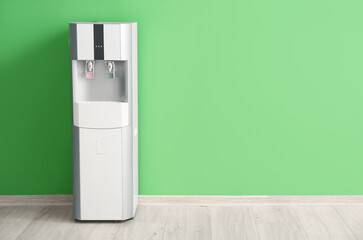 Modern water cooler near green wall