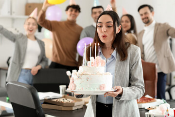 Young woman with Birthday cake making wish at party in office