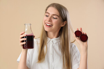 Young woman with bottle of beet juice on beige background