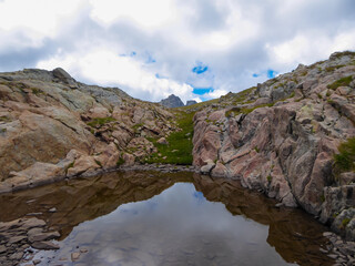 Fototapeta na wymiar Panoramic view of small glacier pond in the Mercantour National Park in the Valley of Marvels near Tende, Provence-Alpes-Côte d'Azur Alpes-Maritimes, France. High mountain ridges in French Alps
