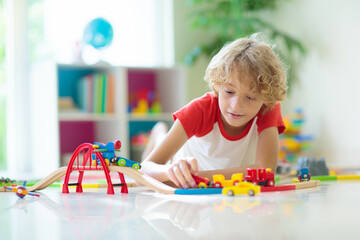 Child with toy train. Kids wooden railway.