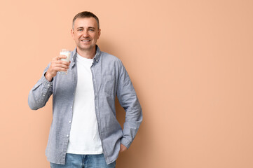 Mature man with glass of milk on beige background