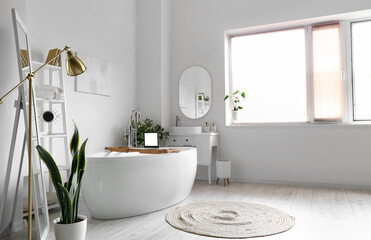 Interior of light bathroom with bathtub, dressing table and shelving unit