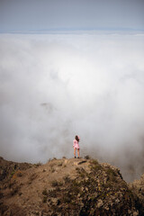 Fototapeta na wymiar Girl standing on a rock above the clouds